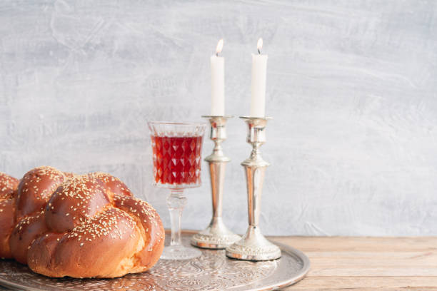 Sabbath kiddush ceremony composition Shabbat or Sabbath kiddush ceremony composition with a traditional sweet fresh loaf of challah bread, glass of red kosher wine and candles on a vintage wood table with copy space jewish sabbath photos stock pictures, royalty-free photos & images