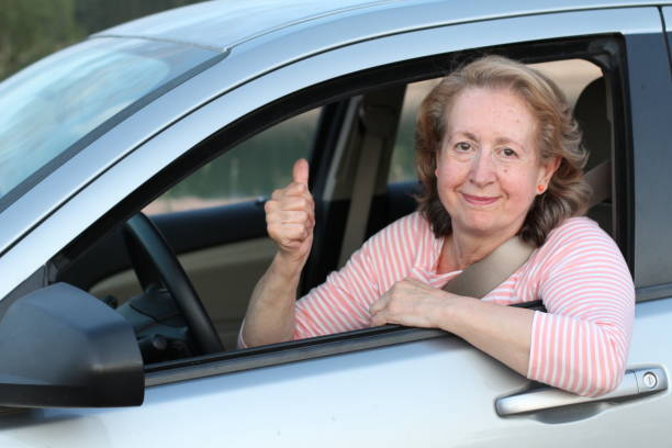 親指を与えるかわいい成熟した女性ドライバー - car insurance driving women ストックフォトと画像