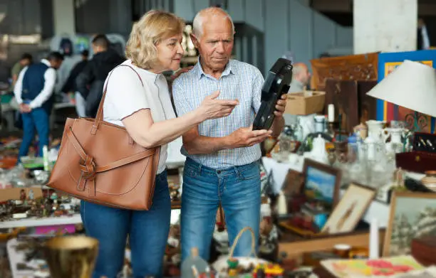 Elderly couple in flea market chooses antique items