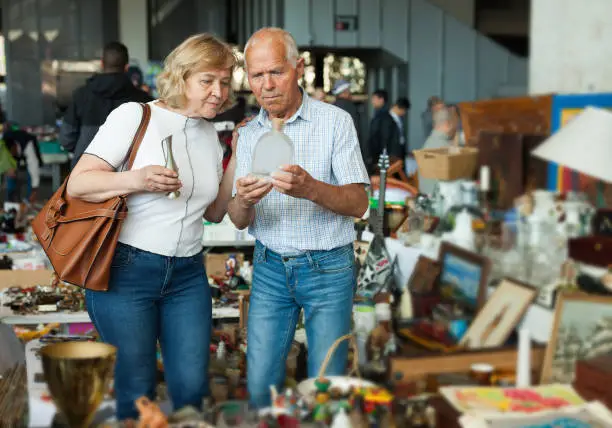 Elderly couple in flea market chooses antique items