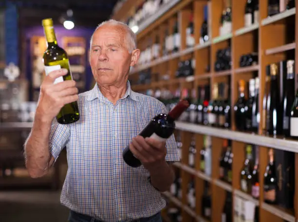 Portrait of senior man visiting winehouse in search of bottle of good wine