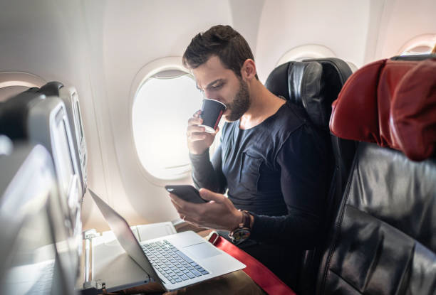 homme travaillant dans l'avion utilisant le téléphone portable et buvant le café - telephone cabin photos et images de collection