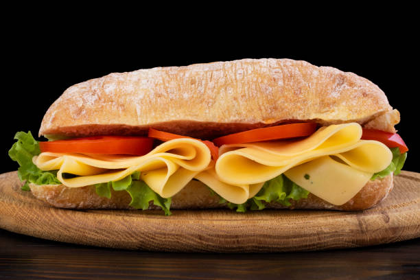 istock Ciabatta sandwich with lettuce , prosciutto and  cheese on wooden board 1164980969