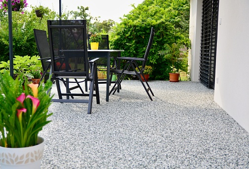 Beautiful Terrace with Decorative Natural Stone Floor, Potted Calla Lily Flower and Table with Chairs.