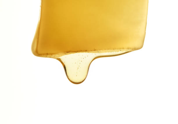 Honey dripping from a piece of cheese. Honey dripping from a piece of cheese. Macro. portion cut out cheese part of stock pictures, royalty-free photos & images