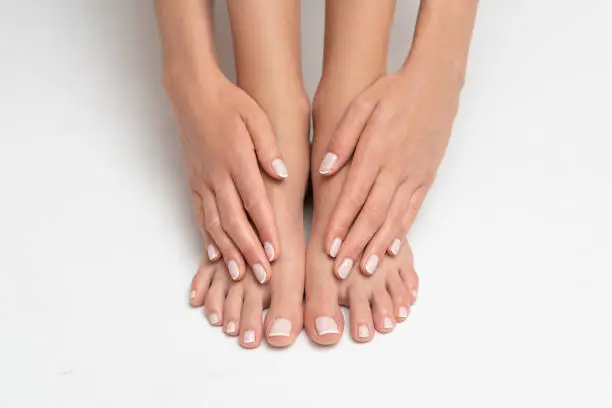 Photo of Perfectly done manicure and pedicure on white background.
