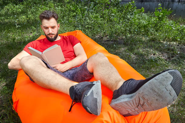 istock Bearded student with book on inflatable lounger. 1165001642