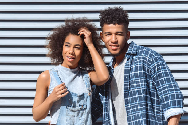istock Young and Free. Couple standing isolated on wall hugging posing confident close-up 1165006123