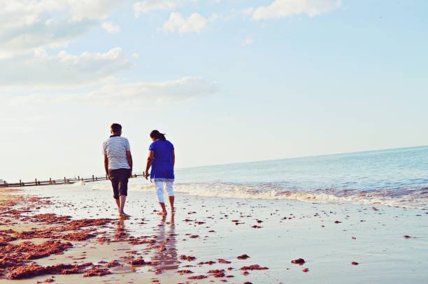 istock An elderly couple taking a walk by the sea on a sandy beach 1165006151