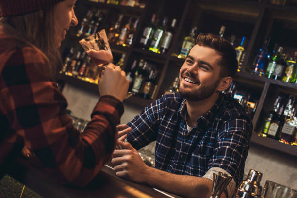 istock Young bartender leaning on bar counter talking with customer happy 1165006401