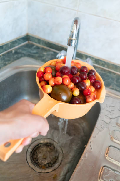 istock hand holding a colander with fresh fruit and berries and washing it in the kitchen with water 1165019424