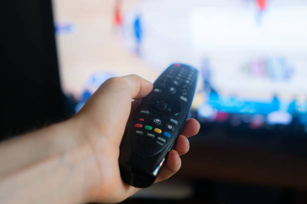 istock hand holding a tv remote, swithing media chanels screen 1165019431