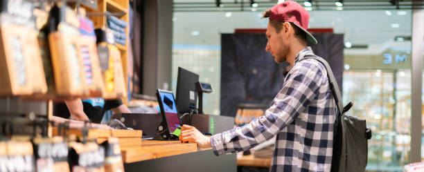 istock young man making a purchase and paying at the cash deck in the store 1165019482