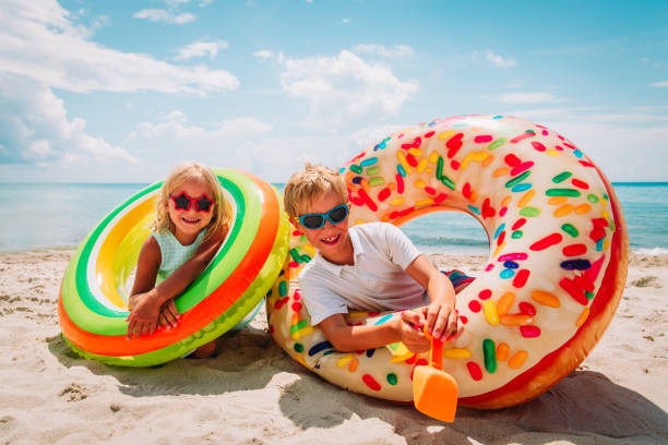 istock happy cute boy and girl play with floaties on beach 1165019869