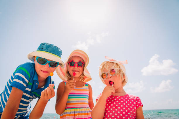 happy kids with lollipops on summer beach vacation