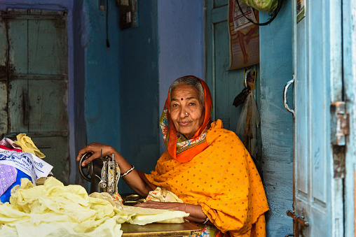 Bikaner, India - February 12, 2019: Indian woman tailor at work place with sewing machine in Bikaner. Rajasthan