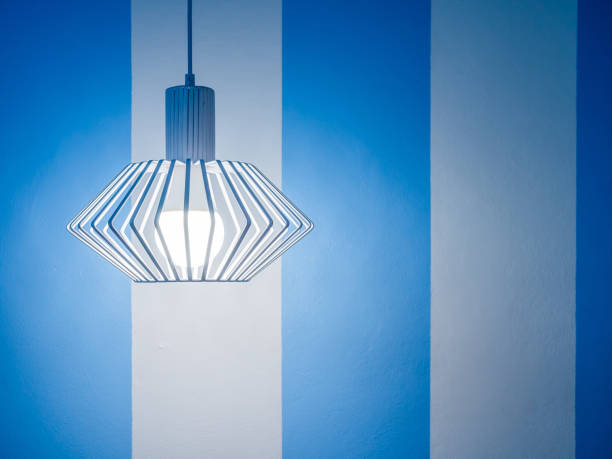 Vintage ceiling lamp on white and blue striped wall background with copy space.
