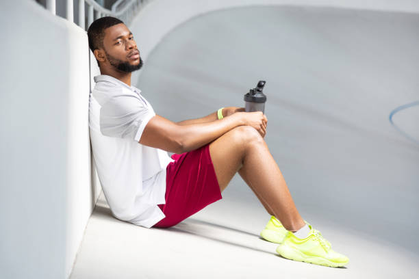 istock Tired handsome young male runner sitting on the ground 1165026759