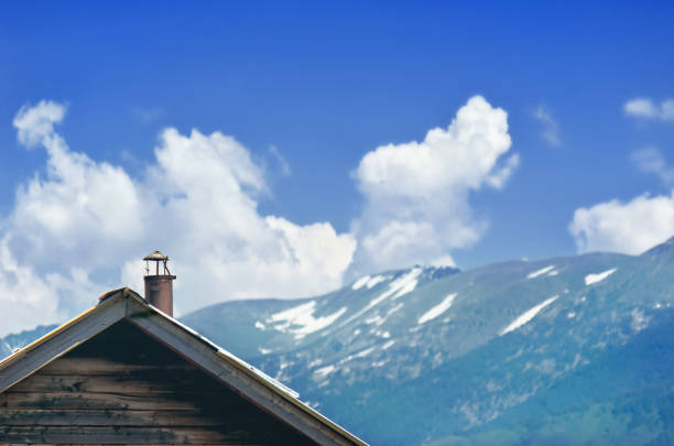 giebel ende eines alten cottage mit horizontalen holz-siding, metall-schornstein. altaigebirge mit weißen schneekappen, kasachstan. - gable end stock-fotos und bilder