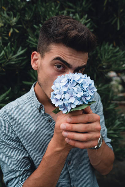 istock Young handsome man is smelling the flowers 1165031515