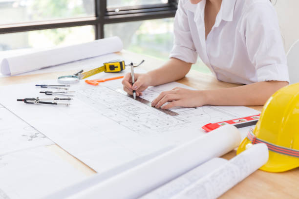 istock Woman asian Architect hands working on blueprint plans with a pencil, a ruler, calculator, smartphone, laptop and engineering 1165040050
