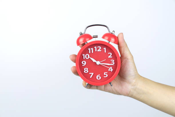istock Hand holding red alarm clock on white background, 1165040260