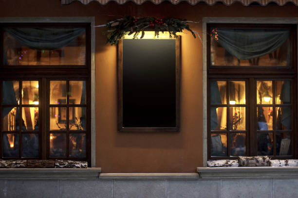 empty sign board for advertising text. christmas luxury decorated store front with garland lights in european city street at winter seasonal holidays. mock up