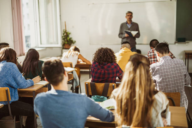 istock Rear view of large group of students attending a class at high school. 1165040310