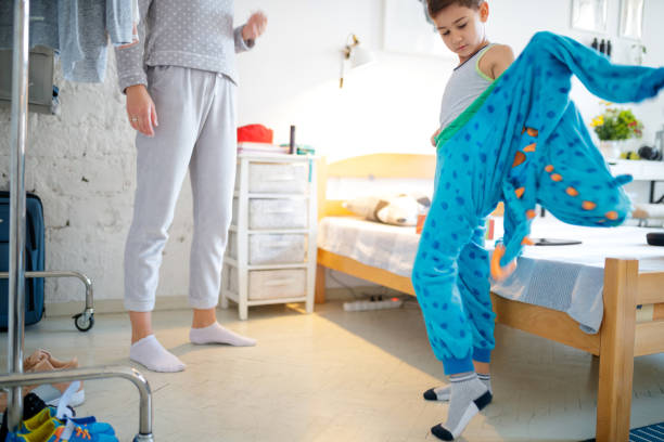 istock Boy putting on his dinosaur pajamas 1165042189
