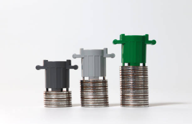 istock Miniature trash cans and piles of coins. 1165045700