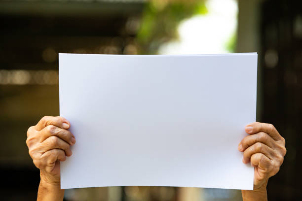 istock Senior woman's Hands holding white paper size A4 in bokeh background, Selective focus, Communication, business concept 1165045899