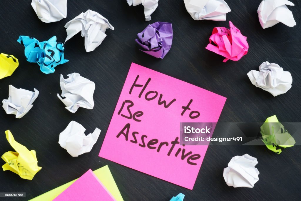 Memo stick with sign How to be Assertive. Assertiveness Stock Photo