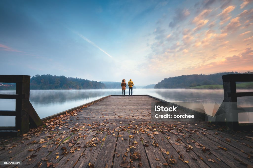 Mindfulness Young couple standing on the jetty and watching sunrise. Landscape - Scenery Stock Photo