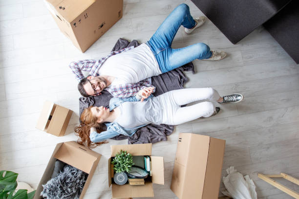 istock Young couple lying at the floor in empty room with unpacked boxes all arround 1165052165