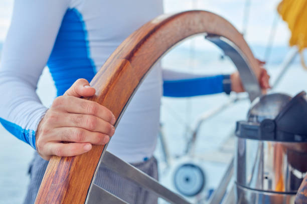 istock Sailor using wheel to steer rudder on a sailing boat. 1165053293