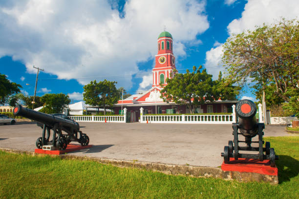 Barbados clock tower Famous red clock tower on the main guardhouse at the Garrison Savannah with old cannons in front of it. UNESCO garrison historic area Bridgetown, Barbados barracks stock pictures, royalty-free photos & images