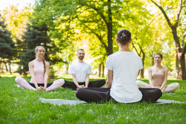 istock Young smiling people practicing yoga lesson with instructor in park 1165063643