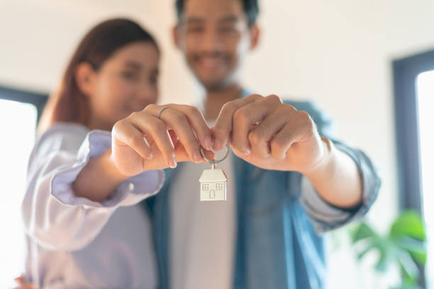 Selective focus at house key chain been hold by young couple after move to new house or apartment and they are feeling happy after moved to new resident. Selective focus at house key chain been hold by young couple after move to new house or apartment and they are feeling happy after moved to new resident. house key photos stock pictures, royalty-free photos & images