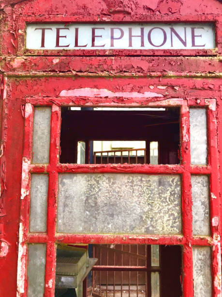istock Image of rusty weathered red telephone box with peeling paint windows, broken glass / London phone box decaying and falling apart in state of disrepair needing restoration in junk yard / reclamation yard, English red telephone kiosk in London, England, UK 1165067010