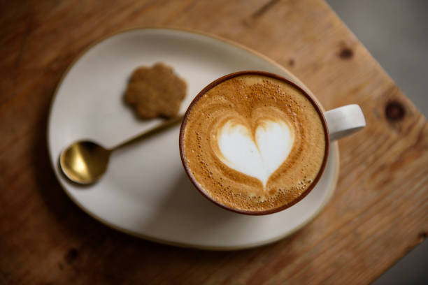 istock Love shape latte art coffee with biscuit and spoon on wooden table 1165068048
