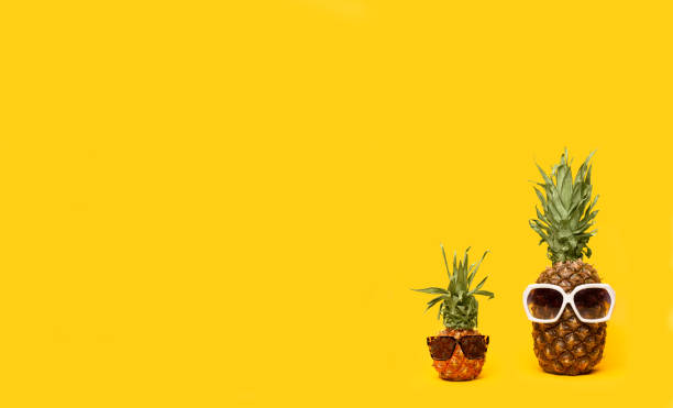 istock Pineapples in sunglasses on a yellow background 1165068936