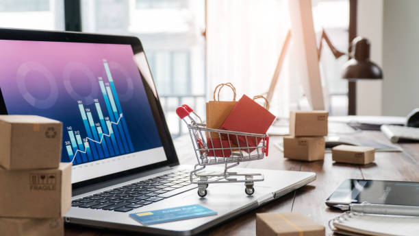 shopping bags in shopping cart and credit card on laptop with paper boxes on table and sales data economic growth graph on screen, buying and selling services online on network, online shopping and e-commerce concept - analyzing graph chart trader imagens e fotografias de stock