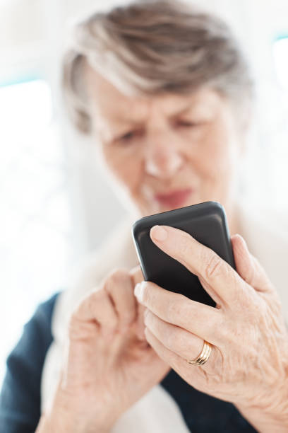 istock Senior woman squinting at mobile phone she's tapping 1165070089