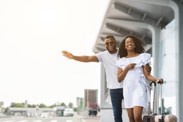 african american man and woman trying to catch taxi, arriving at airport - fazendo sinal com a mão imagens e fotografias de stock