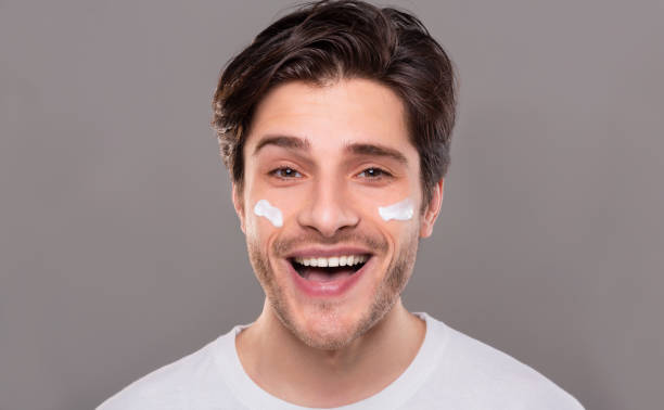istock Cheerful millennial man enjoying pampering cream on face 1165071498