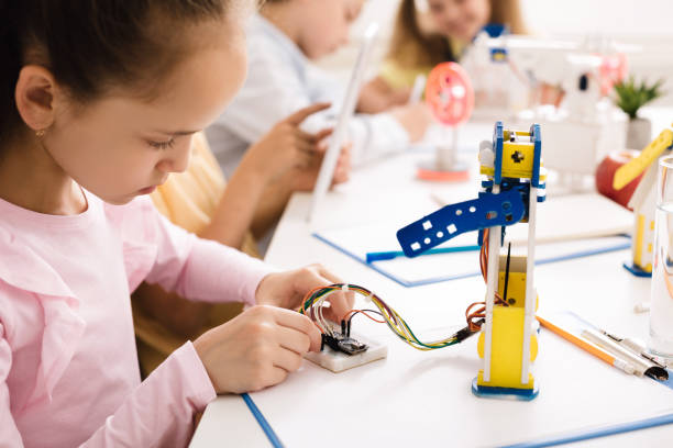istock Girl building robot, working with wires in class 1165073232