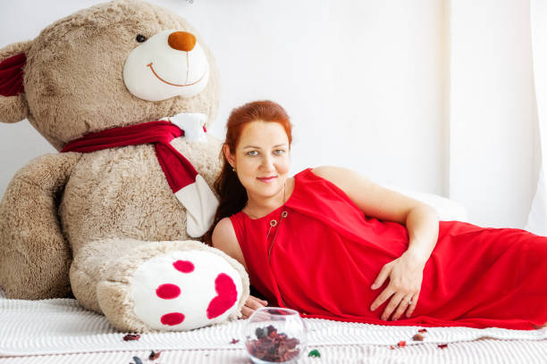 Portrait of a pregnant woman with a big toy bear Portrait of a pregnant woman with a big toy bear bear stomach stock pictures, royalty-free photos & images