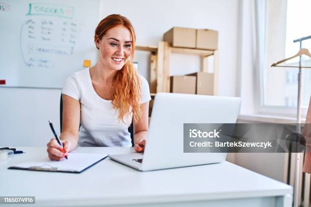 Female Online Business Owner Using Laptop And Documents In Small Office Stock Photo - Download Image Now