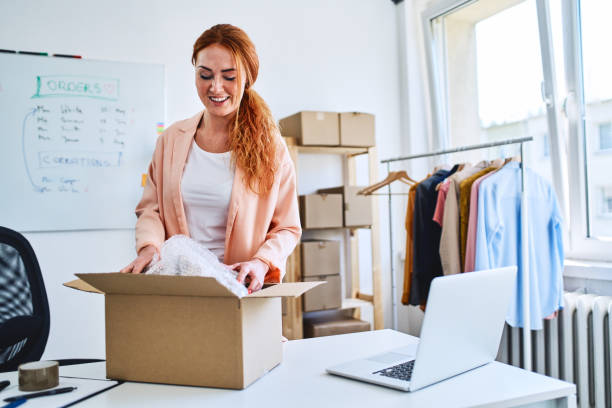 istock Young online store owner packing delivery into cardboard box in office 1165075102