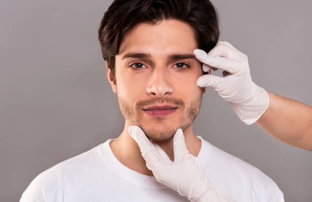 beautician masajeando su rostro de joven hombre guapo - alternative medicine shiatsu massaging spa treatment fotografías e imágenes de stock